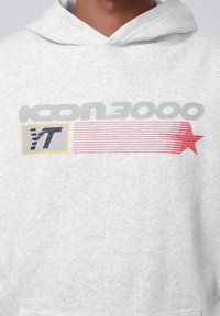 Hanorac gri deschis cu un design grafic, având textul "ICON3000" scris cu litere îngroșate de culoare gri, accentuat cu linii roșii și o stea, completat de detalii galbene.