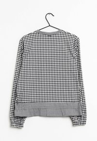 Camisa de manga larga a cuadros en blanco y negro con cuello redondo, puños elásticos y un dobladillo con un diseño de cuadros más ancho.