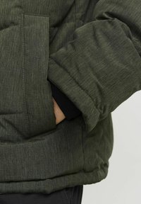 Grüne gepolsterte Jacke mit strukturiertem Finish, ausgestattet mit einer Seitentasche und schwarzen Rippbündchen für zusätzlichen Komfort und Wärme.