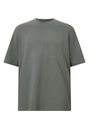 Olijf groene oversized katoenen t-shirt met een ronde hals, korte mouwen en een klein logo detail op de borst. Soepele textuur, ontspannen pasvorm.