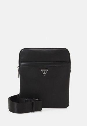 Borsa crossbody nera in materiale sintetico con finitura liscia, chiusura con zip, logo in rilievo sul davanti con un accento metallico triangolare e tracolla regolabile.