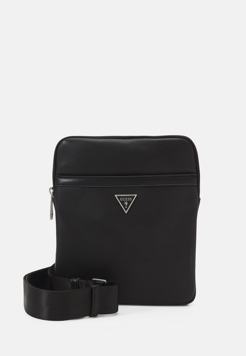 Borsa crossbody nera in materiale sintetico con finitura liscia, chiusura con zip, logo in rilievo sul davanti con un accento metallico triangolare e tracolla regolabile.