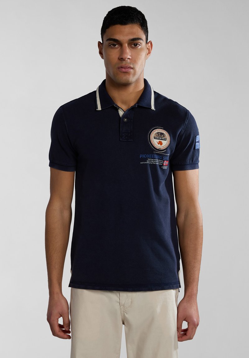 Námořnická modrá polo tričko s kontrastním límcem a vyšitým logem. Krátké rukávy a boční rozparky na spodním lemu. Bavlněný materiál.