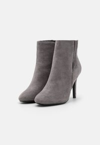 Bottines grises en daim avec un bout pointu et un talon stiletto élancé. Présentent une texture lisse et un design épuré sans ornement supplémentaire.