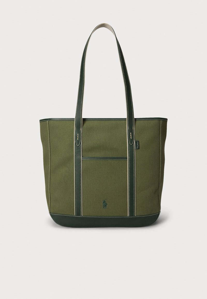 Πράσινη τσάντα tote από καμβά με δύο μακριές λαβές, ορθογώνιο σχήμα, μπροστινή τσέπη, αντίθετη ραφή και μικρό λογότυπο μπροστά.