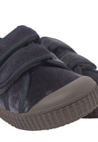 Scarpe velour di un blu scuro con doppie chiusure in velcro. Suola in gomma grigia arrotondata con grip testurizzato. La vista ravvicinata mostra il materiale morbido e i dettagli della costruzione.