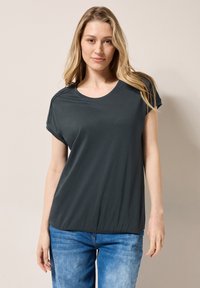 Camiseta corta de manga corta color gris oscuro con cuello redondo, dobladillo elástico y textura suave, combinada con jeans de denim azul claro.
