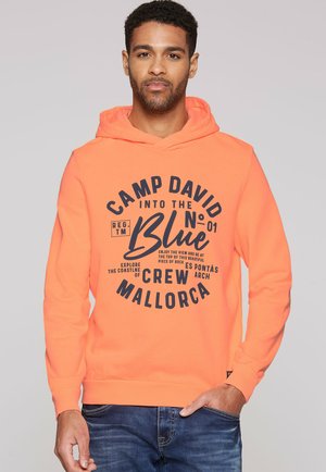 Sudadera naranja con capucha ajustable, que presenta una gran impresión gráfica negra que dice "CAMP DAVID into the Blue" en la parte frontal.