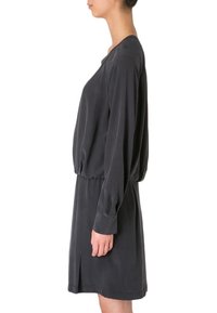 Snygg grå klänning med långa ärmar, lös passform, V-ringning och cinchad midja, med en sidoklyvning för extra detalj och rörelse.