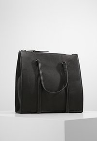 Zwarte lederen handtas met een gestructureerd ontwerp, uitgerust met twee handvatten, een ritssluiting en een textuur. Minimalistische stijl zonder zichtbare accenten.