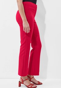 Rode op maat gemaakte broek met een rechte pasvorm, zijzak en gladde stof. Gecombineerd met rode sandalen met bandjes voor een gecoördineerde look.
