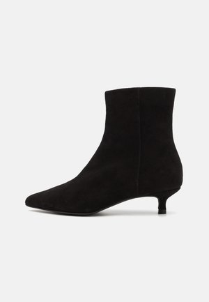 Sorte semskede ankelstøvler med spiss tupp, middels høy hæl og en glatt tekstur. Designet er elegant med minimalistiske detaljer.