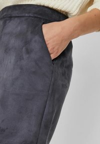 Pantaloni in morbido suede grigio con una texture liscia, dotati di una tasca laterale e una silhouette aderente. La vita è semplice, senza hardware visibili.