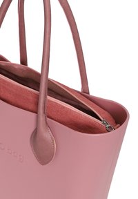 Rosa vattentålig tote-väska med slät yta och robusta handtag. Innehåller en inre ficka med dragkedja i kontrasterande tyg.