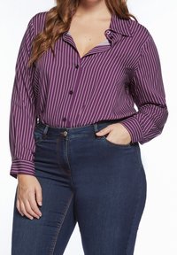 Fialový a bílý pruhovaný dlouhý rukáv s límečkem a knoflíkovou légu, doplněný o tmavé džíny. Má uvolněný střih.