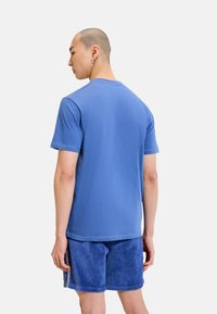 Camiseta de algodón azul de manga corta, con cuello redondo y una textura suave, combinada con pantalones cortos de pana azul con estrías verticales.