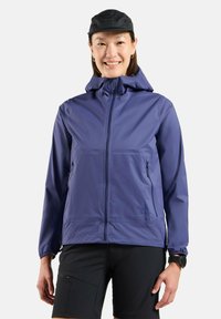Lightweight purple jacket with a hood, front zipper, and side pockets. Smooth texture; worn with black shorts and a black cap.
