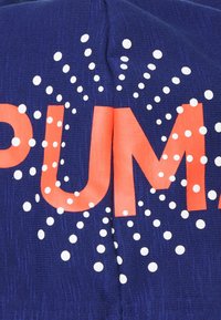 Tissu bleu marine avec le mot « PUMA » en lettres orange vif, entouré d'accents en pointillés blancs, avec un motif de fond texturé.