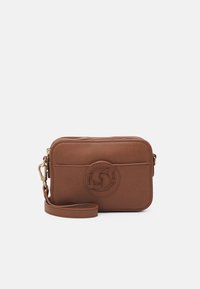 Brązowa skórzana torba na ramię z zamkiem błyskawicznym, z okrągłym akcentem logo, regulowanym paskiem i teksturowaną powierzchnią.