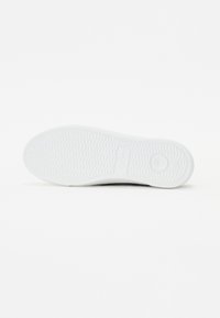 Semelle de chaussure avec motif texturé antidérapant, principalement blanche, posée à plat sur un fond blanc.