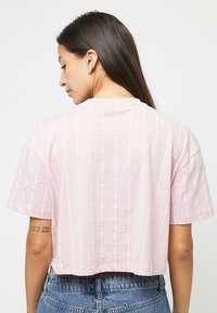 Svetloružové krátke tričko z mäkkej látky, s vertikálnymi bielymi pruhmi, okrúhlym výstrihom a krátkymi rukávmi.