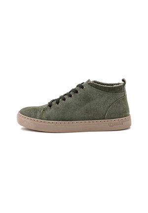 Zapatilla alta de ante verde con cordones negros, suela de goma beige y detalles de costura. Presenta un forro suave en el collar para mayor comodidad.