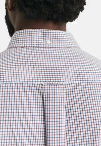 Camicia button-down con un motivo a quadretti in rosso, blu e bianco. Presenta una piega sul retro e un colletto rinforzato con un dettaglio a bottone.