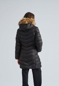 Zwarte pufferjas met een chevronpatroon, een gevoerde capuchon van nepbont en lange mouwen, met een slanke pasvorm en ritssluitingen.