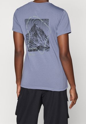 Osoba nosząca lawendowy t-shirt z czarną grafiką zebry i napisem „Never Stop Exploring” ułożonym w okrągły wzór na plecach.