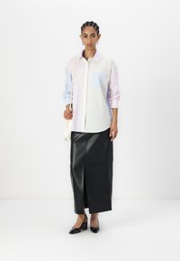 Two-tone button-up shirt in light pastel colors with a striped pocket, paired with a black leather maxi skirt and patent high heels.