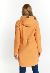 Veste orange imperméable avec capuche, taille à cordon de serrage et poignets à pression. Texture lisse avec un design minimaliste.