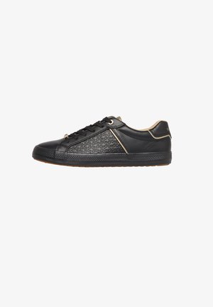 Black low-top sneaker with textured patterned side panel, black laces, beige trim, and gum rubber sole isolated on white background.