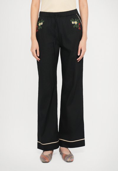 Pantaloni larghi neri con ricami floreali in giallo e rosso, dotati di vita regolabile con coulisse e bordo a contrasto ai polsini.