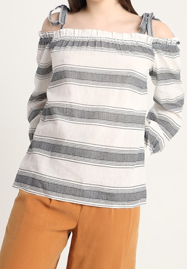 Vit off-the-shoulder blus med svarta ränder, volangkrage och knytband på axlarna. Lättviktsmaterial med en avslappnad passform.