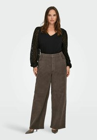 Brązowe spodnie szerokie z sztruksu z wysokim stanem, zestawione z czarnym topem z dekoltem w serek i koronkowymi rękawami. Gładka faktura i klasyczny design.