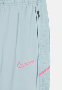 Shorts de sport bleu clair avec une texture en mesh respirant, des accents roses et un logo Nike cousu sur le côté gauche.