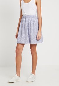 Light purple skirt with an elastic waistband, featuring white floral embroidery patterns and a flared shape, paired with white sneakers.