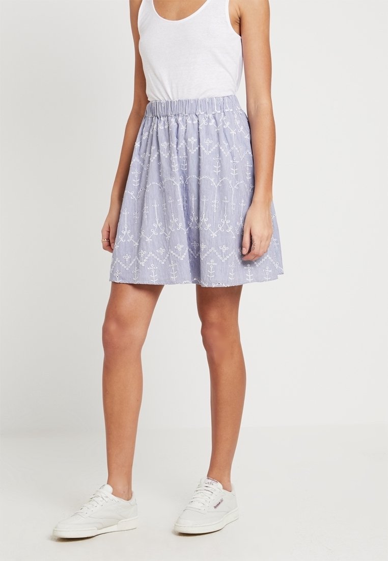 Light purple skirt with an elastic waistband, featuring white floral embroidery patterns and a flared shape, paired with white sneakers.