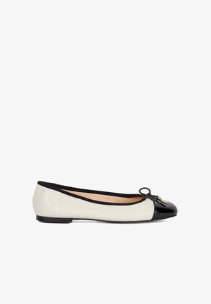 Ballet flat shoe with a cream leather upper, black patent leather toe cap, black trim, and decorative bow with small gold hardware.