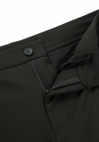 Pantaloni neri con tasca con zip, chiusura con bottone e vita texture. Presenta dettagli di cucitura vicino alla zip.