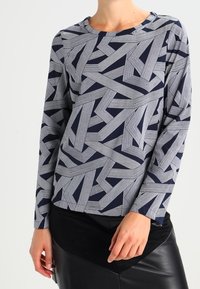 Maglietta a maniche lunghe con un motivo geometrico a righe blu navy e bianche, scollo rotondo, realizzata in tessuto morbido con una vestibilità comoda.