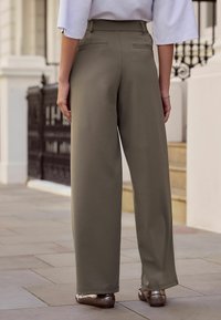 Khakinväriset leveälahkeiset housut, joissa on korkea vyötärö ja takataskut, yhdistettynä metallinhohtoisiin balleriinoihin. Sileä kangas ja rento istuvuus.