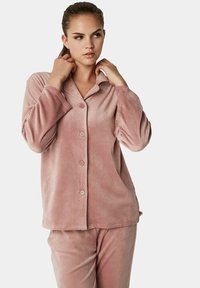 Roze fleece lounge-set met een knoopsluiting aan de bovenkant, een kraag en lange mouwen, gecombineerd met bijpassende broek, gladde textuur.