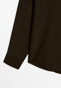 Mørkebrun langærmet skjortefragment, glat tekstur, buet kant og en knaplukning ved manchetterne med syningsdetaljer.