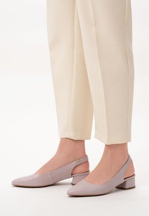 Jasnofioletowe buty typu slingback z noskiem w kształcie spiczastym i niskim słupkowym obcasem, wykonane z gładkiego materiału. Stylizowane z wąskimi kremowymi spodniami.
