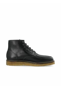 Botas de cuero negro hasta el tobillo con punta redonda, diseño de cordones de seis ojetes y suela de goma beige en contraste. Textura suave con costuras simples.