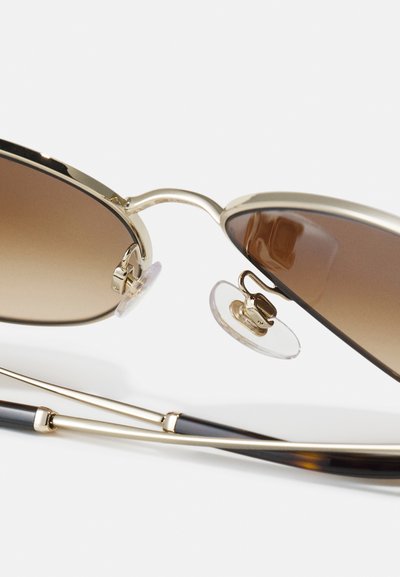 Gold-framed sunglasses with brown gradient lenses. Features adjustable nose pads and thick, patterned dark tortoiseshell temples.