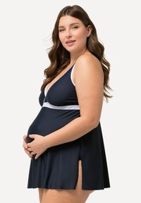 Těhotenské plavky v námořnické modři s bílým lemem, s hlubokým výstřihem do V, rozšířenou sukní a postranními rozparkami pro pohodlí. Hladký, elastický materiál.
