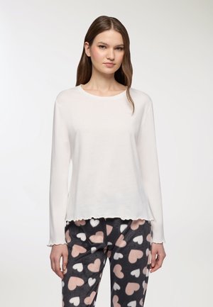 Top bianco a maniche lunghe realizzato in tessuto morbido, con scollatura rotonda e orlo Sagomato, abbinato a pantaloni del pigiama grigi con motivi a cuore.