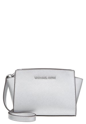 Petit sac bandoulière argenté Michael Kors avec une lanière pour poignet et une finition texturée, présenté sur fond blanc.